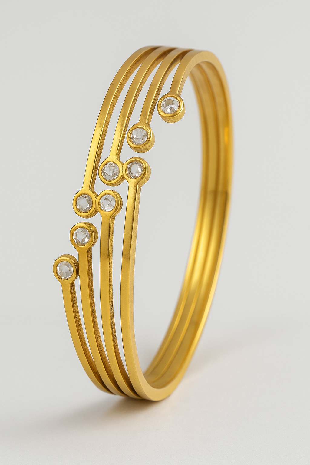 Gold bracelet with embedded stones on a light gray background