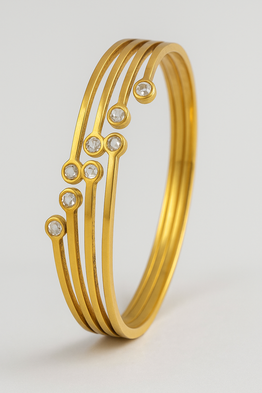 Gold bracelet with embedded stones on a light gray background