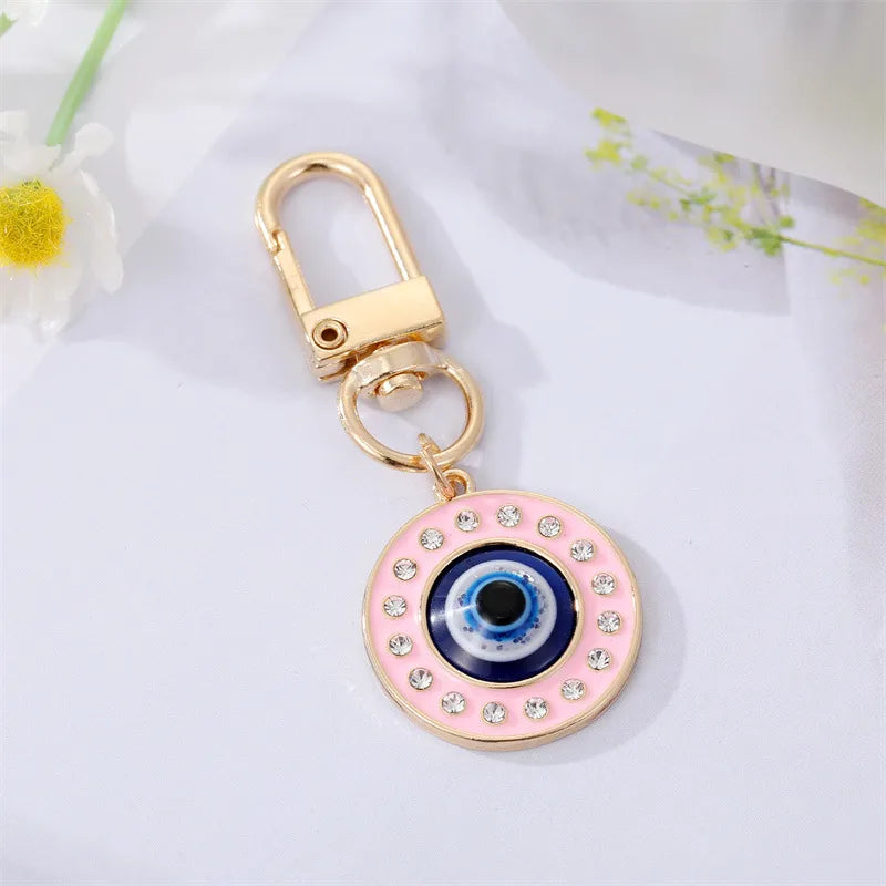 Pink evil eye keychain with gold clasp on a light background