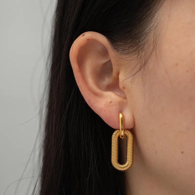 Gold hoop earring worn by a person with a neutral background